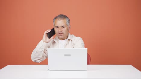 Hombre-Usando-Una-Computadora-Portátil-Hablando-Nerviosamente-Por-Teléfono.